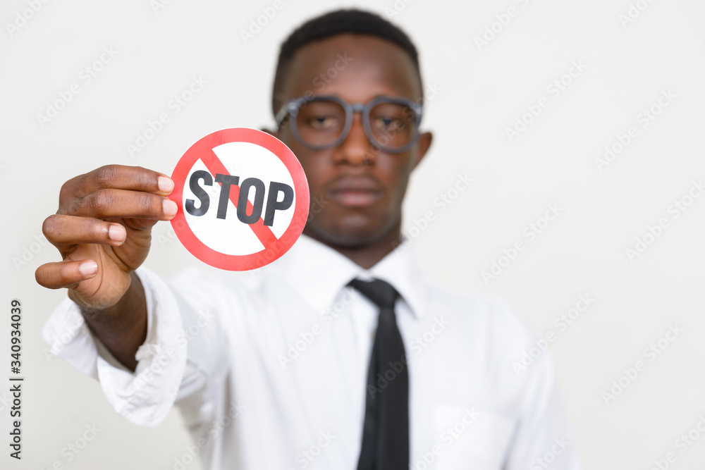 Face of young African businessman holding stop sign Face of young African businessman holding stop sign