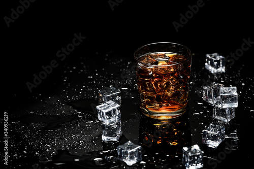 Whiskey with ice cubes on black background from above.Glass of scotch and ice cubes on a on black background