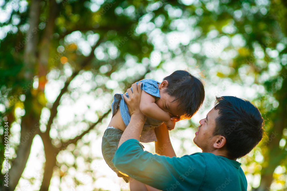 Portrait of happy father holding baby son hand carry up in city park sunset light. Portrait of happy father holding baby son hand carry up in city park sunset light.