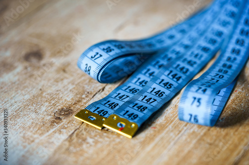 Blue measuring tape on wooden table. Tailor concept. Close-up. photo