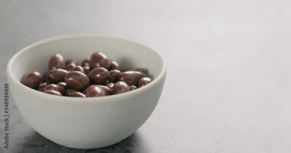 Slow motion chocolate covered pistachio fall in white bowl with copy space Slow motion chocolate covered pistachio fall in white bowl with copy space