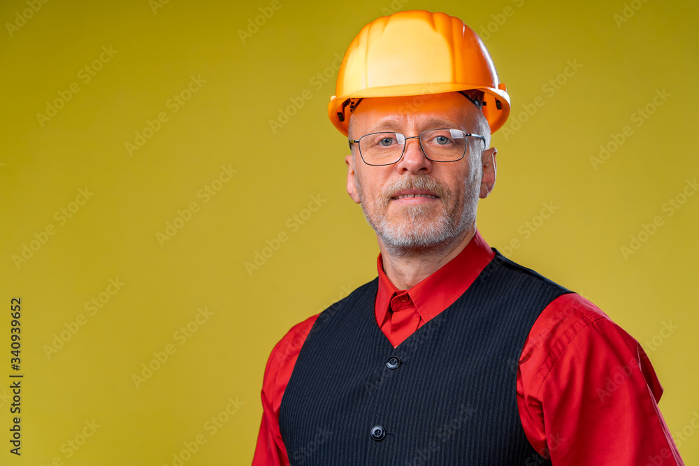Positive senior engineer in a helmet on a yellow background. Positive senior engineer in a helmet on a yellow background.