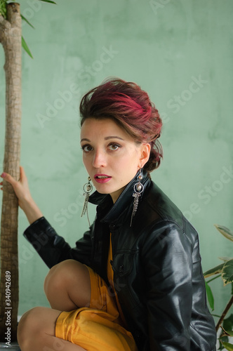 Glam rock style look of a beautiful girl with dark pink hair and mohawk wearing yellow dress and black leather jacket, close-up female portrait