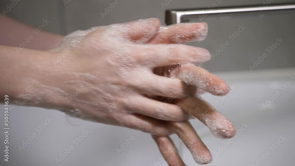 A woman washes her hands with soap over a white sink to eliminate germs and protect against the virus. A woman washes her hands with soap over a white sink to eliminate germs and protect against the virus.