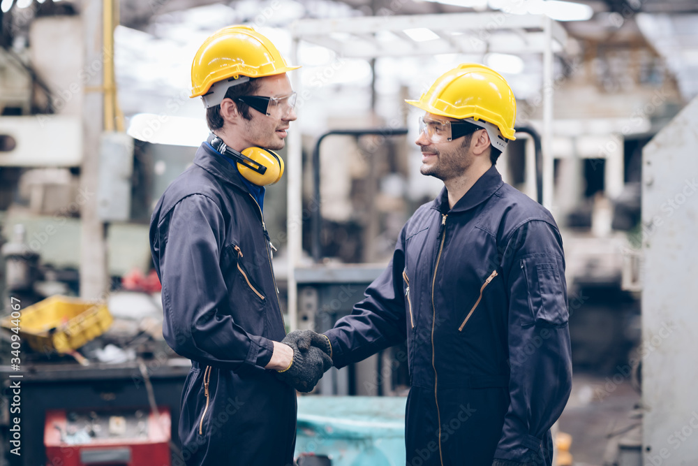 technician and partnership shake hand at machine in factory technician and partnership shake hand at machine in factory