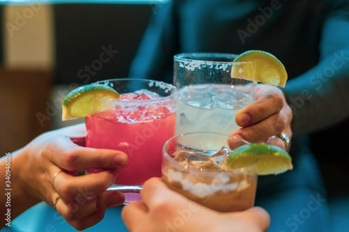 Friends toasting (cheers) with margaritas of different flavors photo
