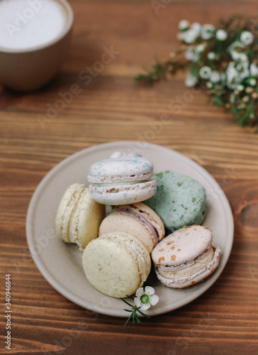 Colorful homemade macarons are lying on the brown wooden background.Cup of coffee. 