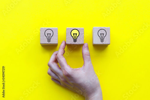 Concept of a new idea, wooden cubes with a light bulb icon on a yellow background