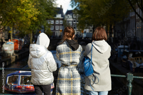 Tourists standing on a bridge looking at an Amsterdam canal