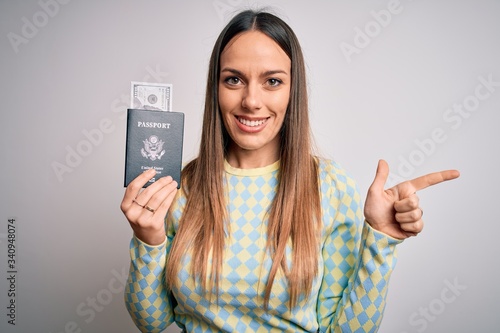 Young blonde tourist woman holding id passport with dollar as money for vacation very happy pointing with hand and finger to the side