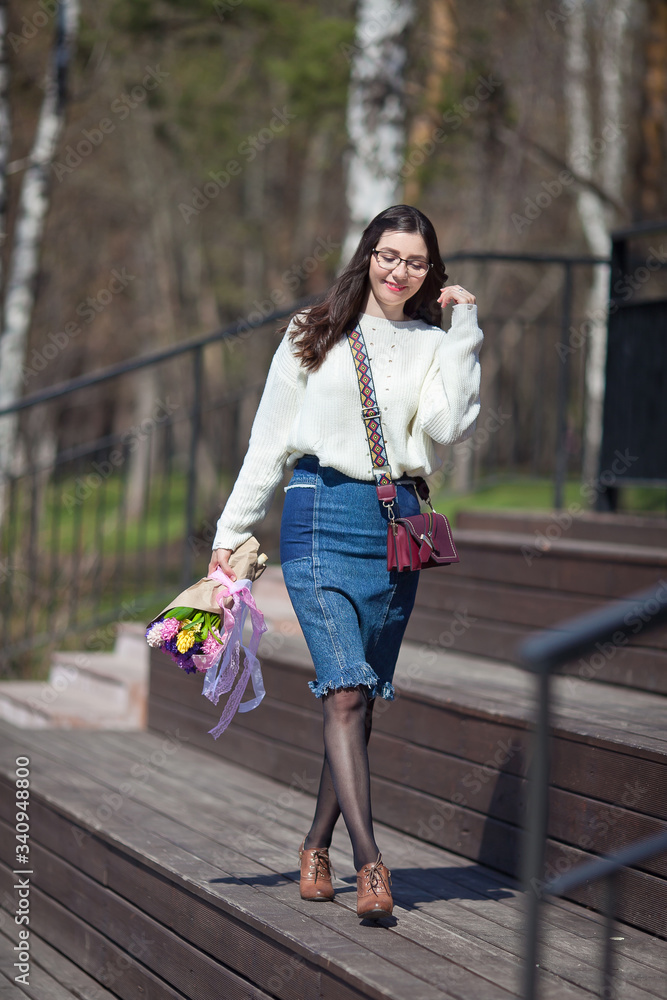 beautiful girl walks with a bouquet of spring flowers along the promenade