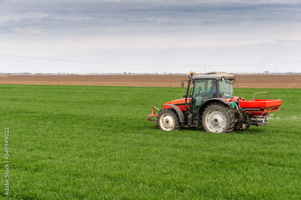 Obraz premium Tractor spreading artificial fertilizers