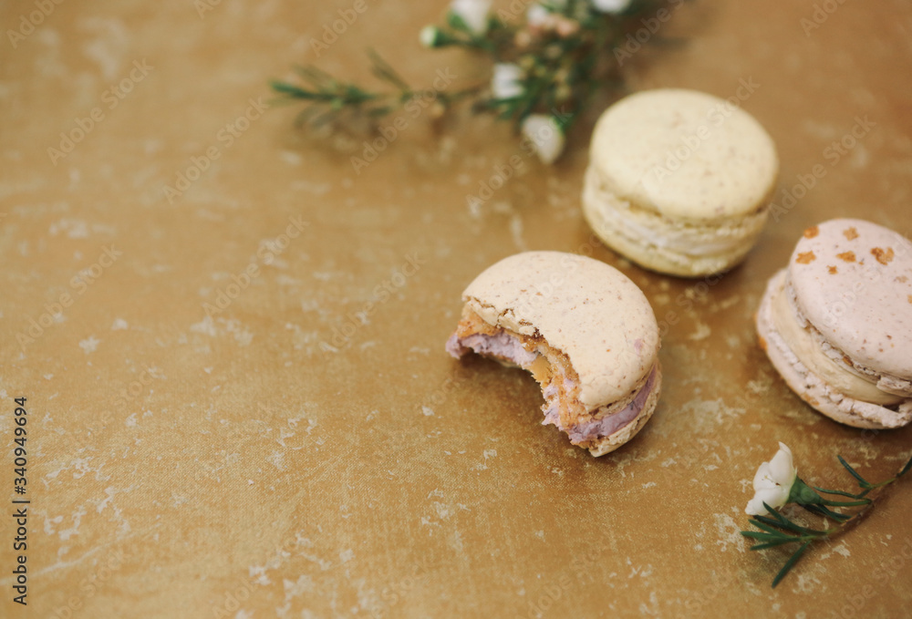 Three homemade macarons with blossom are lying on the golden background. Three homemade macarons with blossom are lying on the golden background.