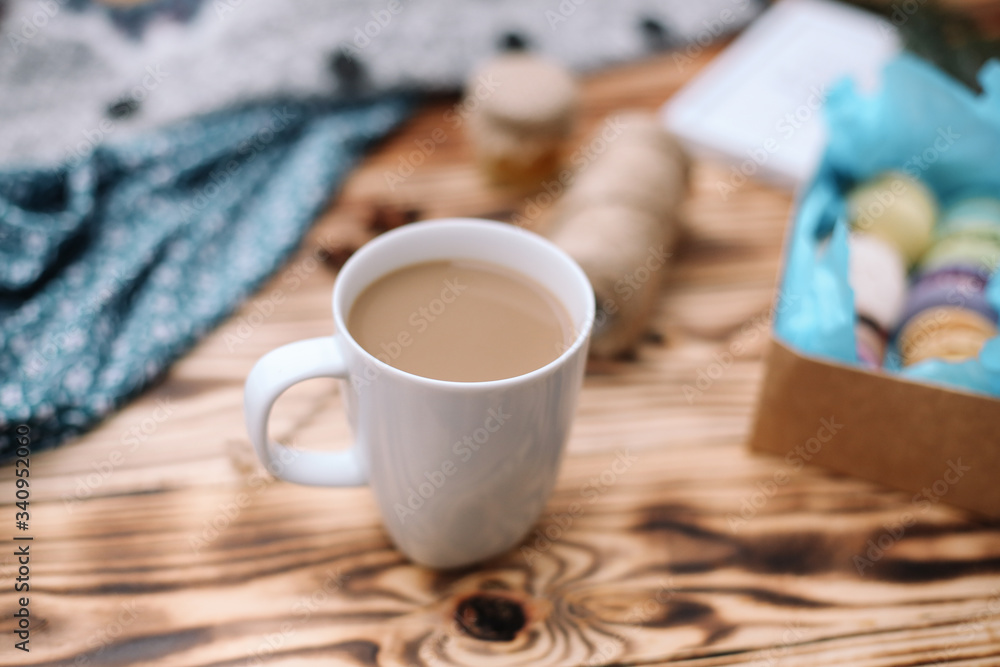 Two homemade colorful macaroons are lying on the brown wooden table with cup of coffee. Cup of coffee. Colorful tissue. Two homemade colorful macaroons are lying on the brown wooden table with cup of coffee. Cup of coffee. Colorful tissue.