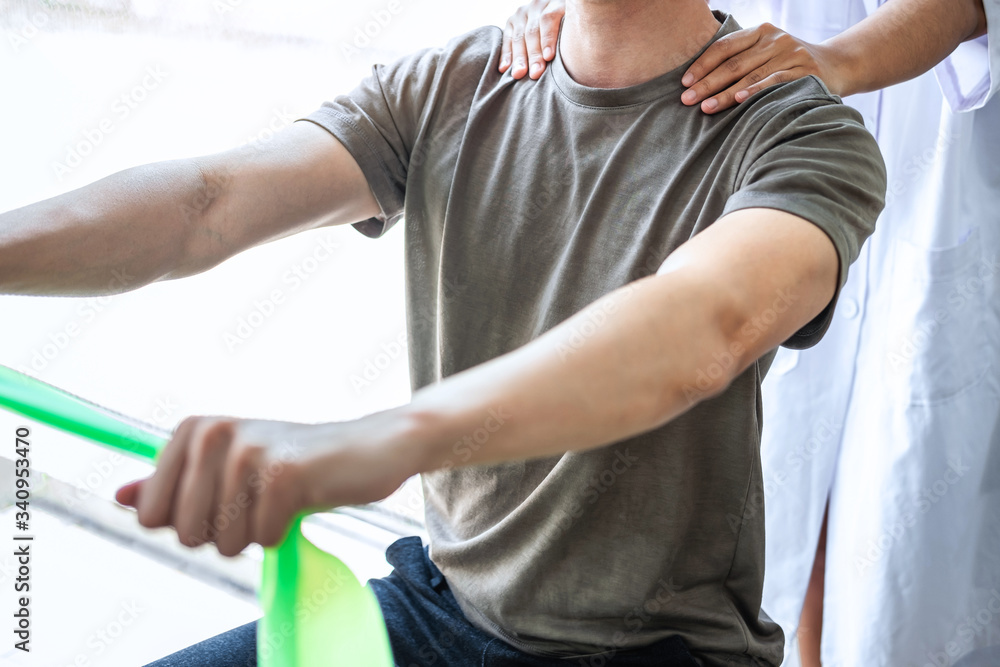 Doctor or Physiotherapist working examining treating injured arm of athlete male patient, stretching and exercise, Doing the Rehabilitation therapy pain in clinic Doctor or Physiotherapist working examining treating injured arm of athlete male patient, stretching and exercise, Doing the Rehabilitation therapy pain in clinic