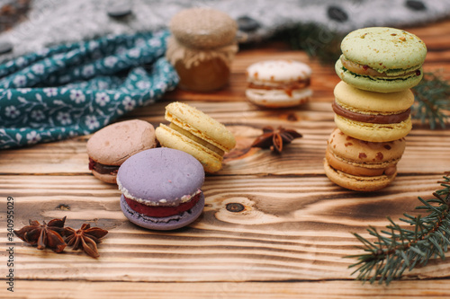 Homemade colorful macaroons are lying on the brown wooden table. Cup of coffee. Anise, honey and colorful tissue.