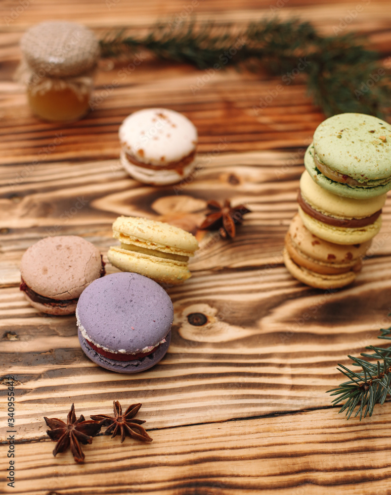 Homemade colorful macaroons are lying on the brown wooden table. Cup of coffee. Anise and honey.