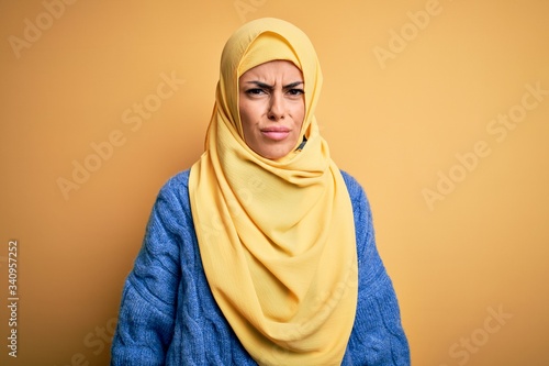 Young beautiful brunette muslim woman wearing arab hijab over isolated yellow background skeptic and nervous, frowning upset because of problem. Negative person. © Krakenimages.com