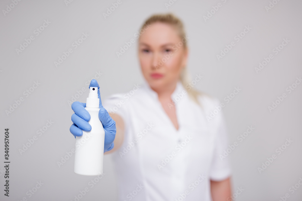 health care, hygiene and corona virus pandemic concept - female doctor, nurse or cosmetologist in white uniform spraying disinfective liquid over gray health care, hygiene and corona virus pandemic concept - female doctor, nurse or cosmetologist in white uniform spraying disinfective liquid over gray