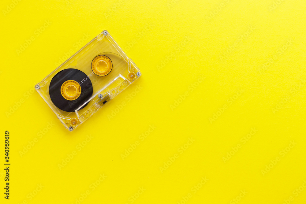 Retro audio tape cassette from 80s and 90s isolated on yellow background. Old technology concept. Flat lay, top view with copy space. Retro audio tape cassette from 80s and 90s isolated on yellow background. Old technology concept. Flat lay, top view with copy space.