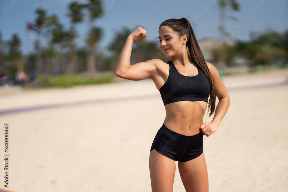 Strong fitness woman showing arms biceps towards the sea. Healthy lifestyle motivation and success. Strong fitness woman showing arms biceps towards the sea. Healthy lifestyle motivation and success.