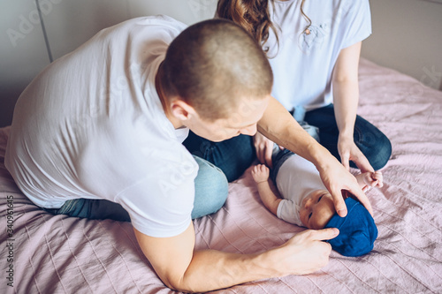 Close up portrait of a happy parents holding their baby. Young happy family, mom and dad playing with cute emotional little newborn child son in the bedroom