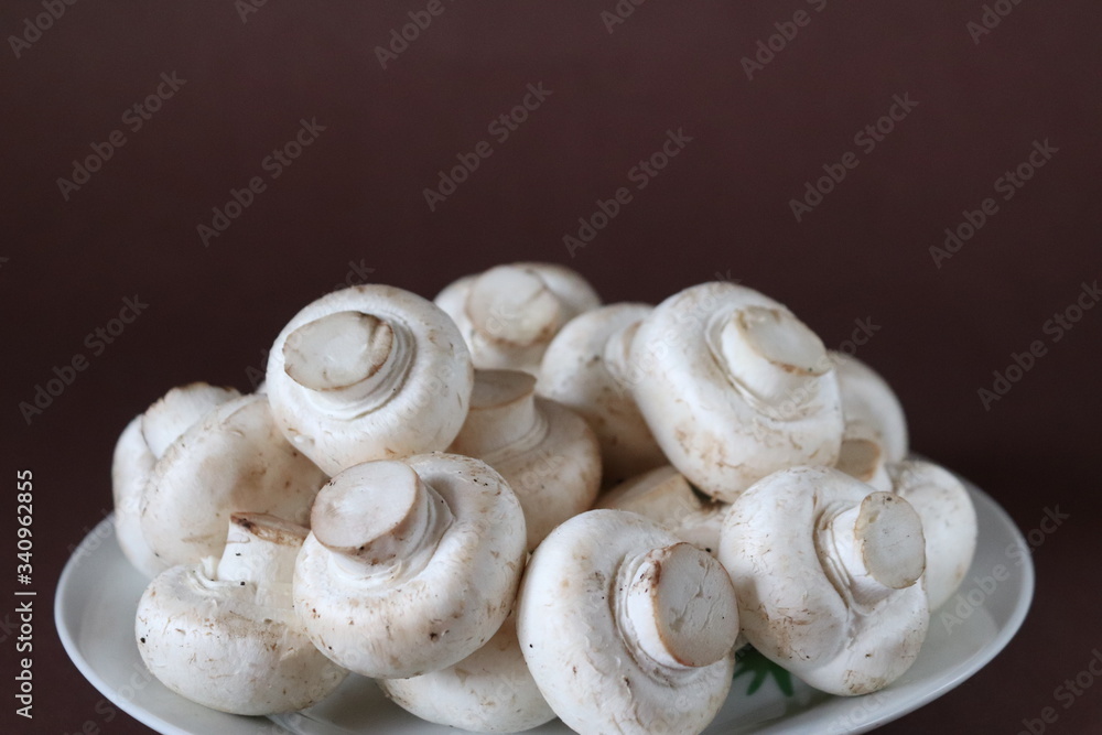 raw mushrooms on a plate on dark brown background raw mushrooms on a plate on dark brown background