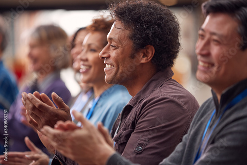 Group Of Casually Dressed Businessmen And Businesswomen Applauding Presentation At Conference