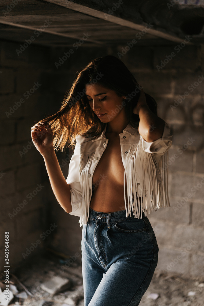Seductive young gorgeous woman in stylish clothes touching hair while standing inside ruined stone building Seductive young gorgeous woman in stylish clothes touching hair while standing inside ruined stone building