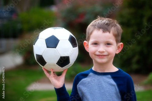 cute young boy playing soccer in back yard