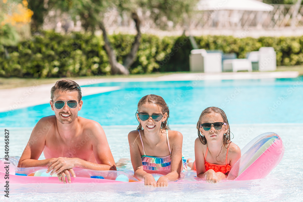 Happy family of three in outdoors swimming pool