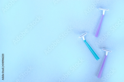 disposable razors of different colors on a blue background © Aleksandra Iarosh