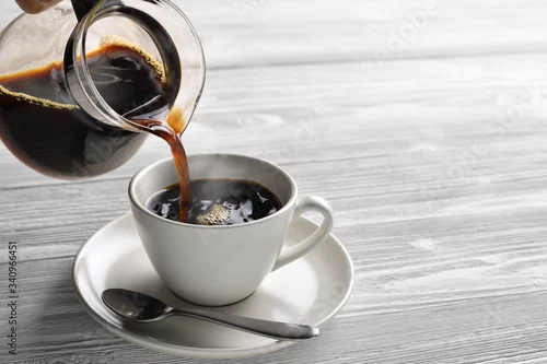 Obraz Pouring coffee with smoke on a cup on wooden background