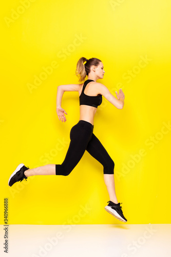 Fototapeta Naklejka Na Ścianę i Meble -  young woman doing exercise on yellow background