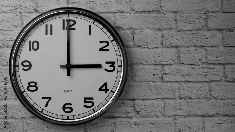 The Time On The Clock Three. A Clock On A White Brick Wall With The Black Arrow Running In The Background Of The Arabic Numerals. Timelapse.. The Time On The Clock Three. A Clock On A White Brick Wall With The Black Arrow Running In The Background Of The Arabic Numerals. Timelapse..
