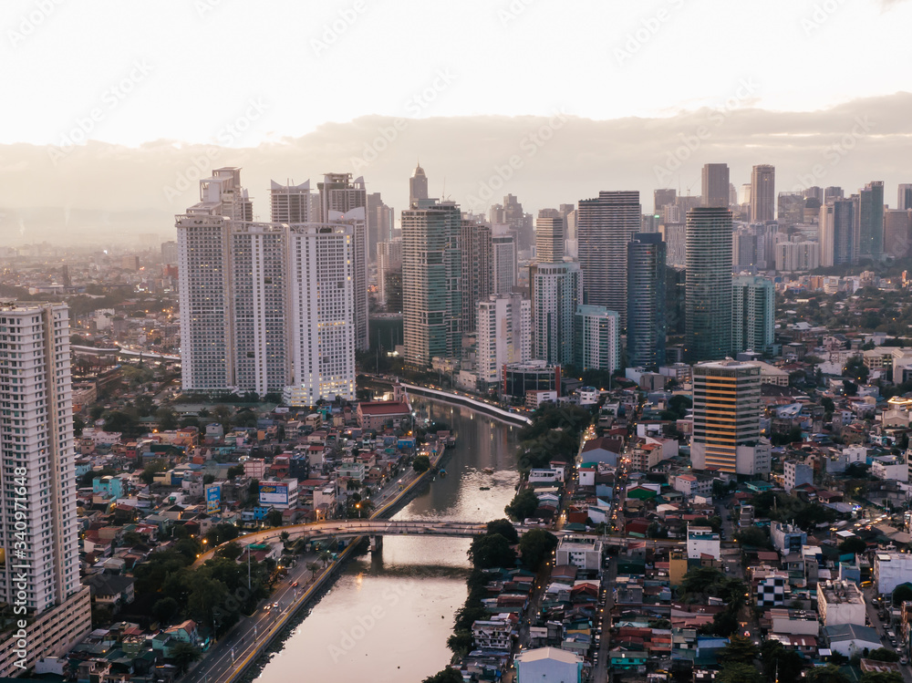 Aerial drone shot of the Skyline of Makati City in Metro Manila, Philippines while sunrise with the Pasig River in the centre of the frame
