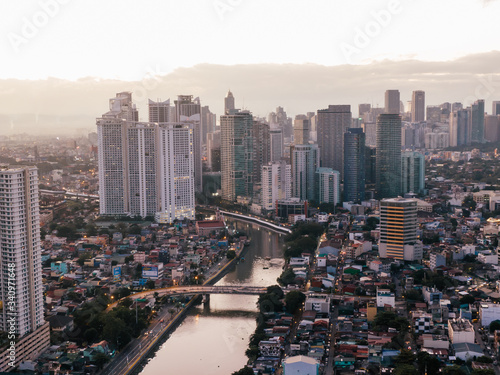 Aerial drone shot of the Skyline of Makati City in Metro Manila, Philippines while sunrise with the Pasig River in the centre of the frame photo