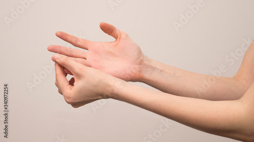 Close-up of female hands holding her painful wrist caused by prolonged work on a computer  laptop. Carpal tunnel syndrome  arthritis  neurological disease.