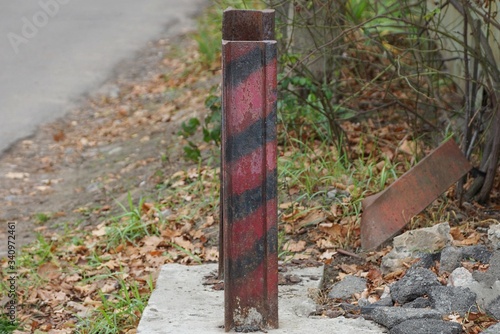 Wallpaper Mural one striped iron fence post from an old rail stands on the street by the road Torontodigital.ca