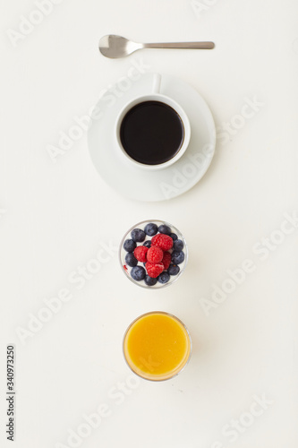 Top view at minimal composition of delicious dessert decorated with fresh berries next to coffee cup on white background, breakfast concept, copy space