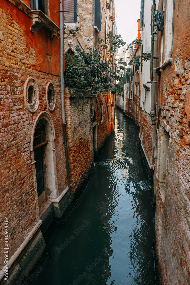A narrow channel of water between the residential houses of red brick | VENICE, ITALY - 16 SEPTEMBER 2018. 