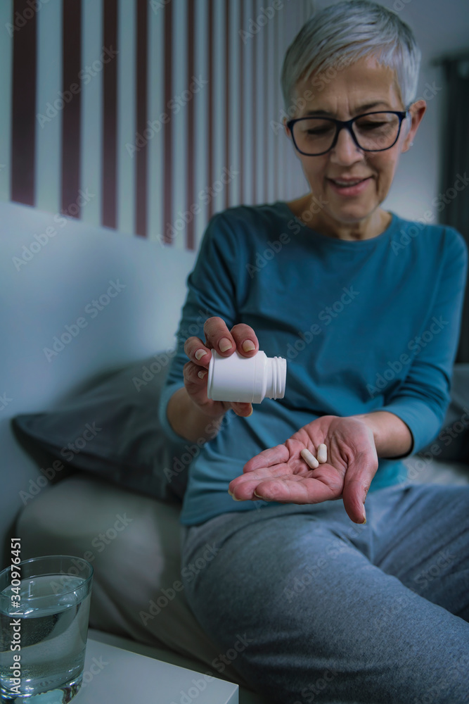 Melatonin sleeping pills. Senior woman taking sleeping pills before bedtime Melatonin sleeping pills. Senior woman taking sleeping pills before bedtime