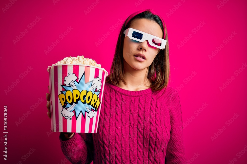 Obraz premium Young beautiful girl watching movie using 3d glasses eating box with popcorns looking sleepy and tired, exhausted for fatigue and hangover, lazy eyes in the morning.