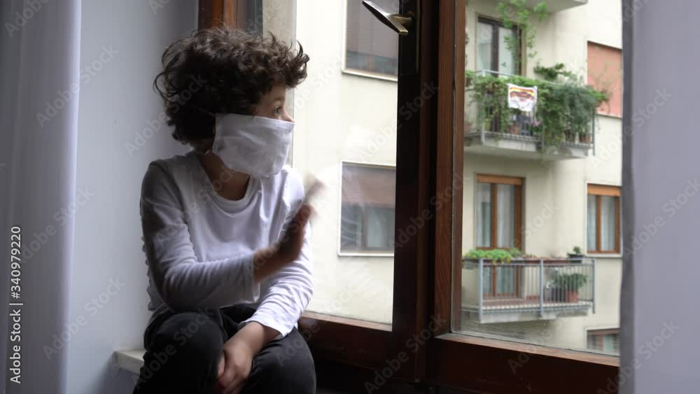 Europe, Italy , Milan - children boy five years with mask at home during quarantine at home due n-cov19 Coronavirus outbreak - life style in apartment - look and say hello from the window rainy day Europe, Italy , Milan - children boy five years with mask at home during quarantine at home due n-cov19 Coronavirus outbreak - life style in apartment - look and say hello from the window rainy day