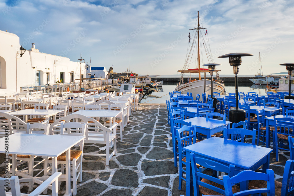 Fototapeta premium Cafe tables on quay of Naousa town port in famous tourist attraction Paros island, Greece on sunrise