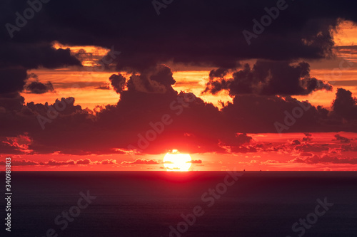 Sunset over horizon in tropical sea with cloudy