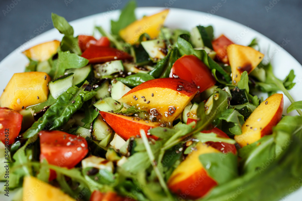 Close up food photo of the healthy salad made of arugula, cherry tomatoes, spinach, avocado, nectarine, chia seeds and sprinkled with olive oil and balsamic vinegar. Close up food photo of the healthy salad made of arugula, cherry tomatoes, spinach, avocado, nectarine, chia seeds and sprinkled with olive oil and balsamic vinegar.