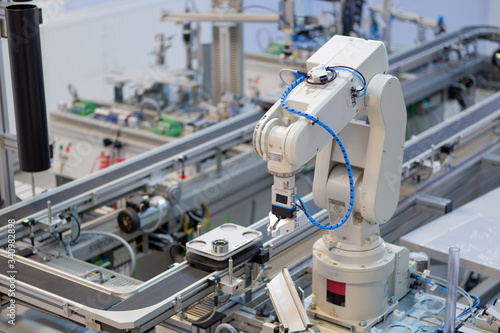 Industry 4.0 concept; artificial intelligence in smart factory prototype. Robot arm picks up the product from automated car on production line. Focus on automated car. Selective focus.
