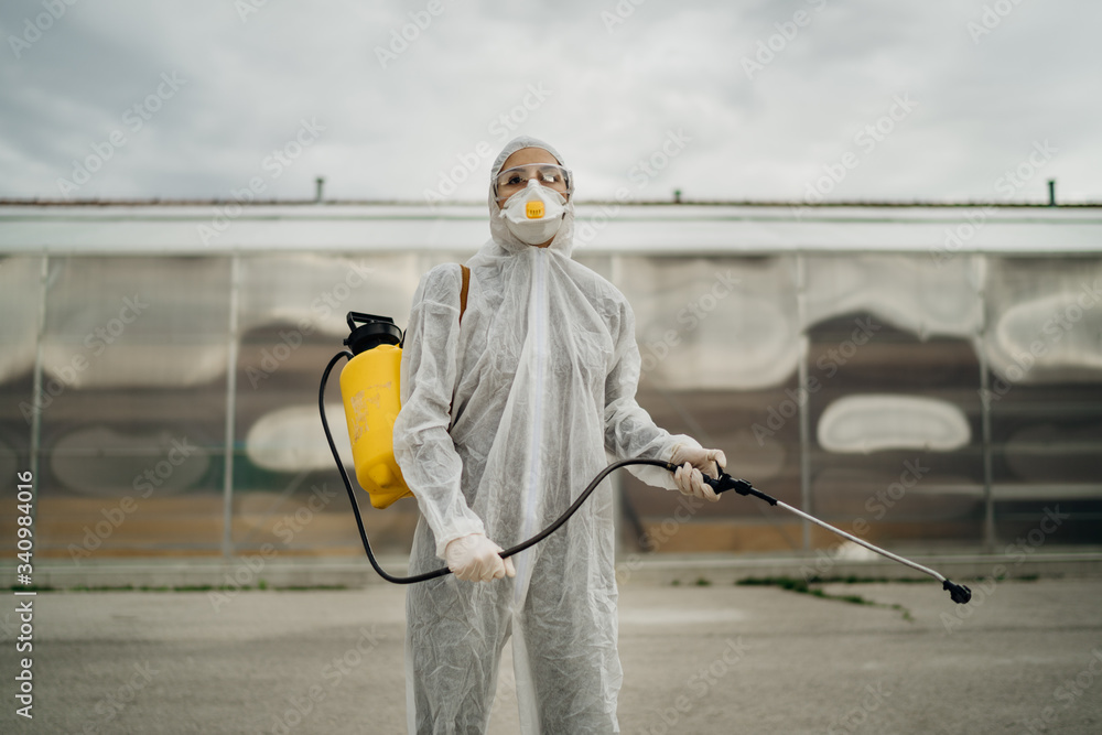 Disinfection specialist in private protective equipment (PPE) performing public decontamination.Hazmat suit virus protection. COVID-19 outbreak worker.Quarantined area.Dangerous hazard environment.
