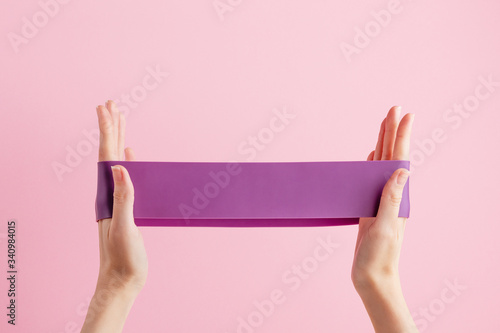 Obraz na płótnie Woman stretch fitness band. Violet rubber for home exercises. Indoor and outdoor workout. Sport and healthy active lifestyle concept. Isolated on pink background w salonie